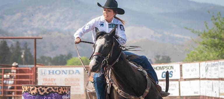 Barrel racer Alex Simpson Segyra completing a turn around a barrel on her horse.